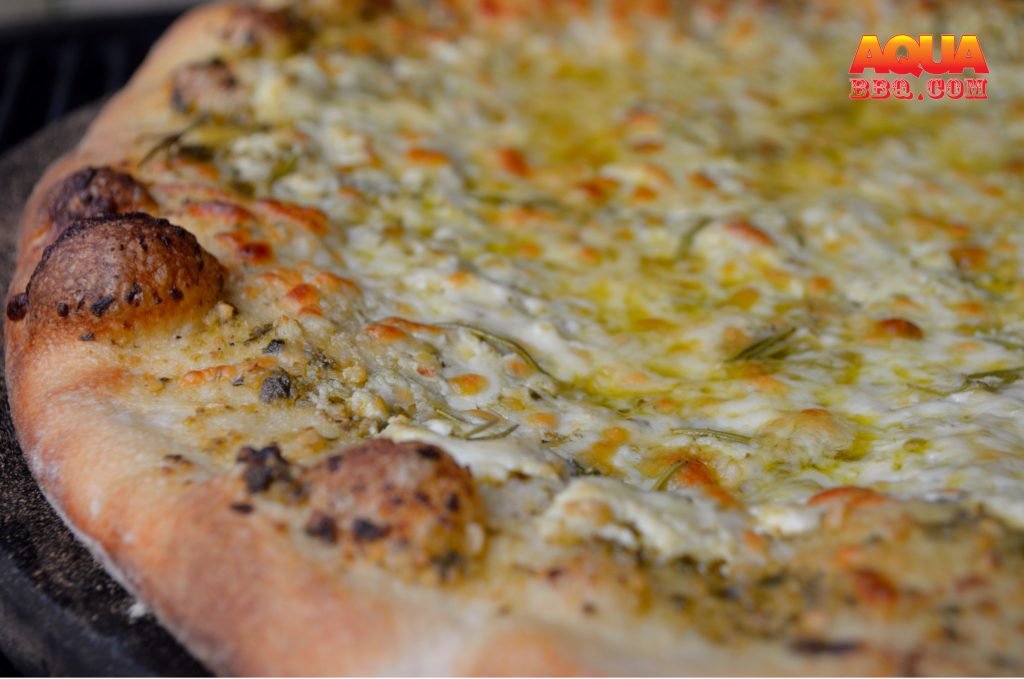 White Pizza on the Primo with ricotta, pesto, rosemary, and mozzarella.